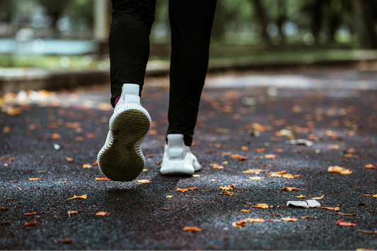 person walking on a trail with leaves on the ground